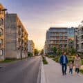 Late afternoon in Sarcelles showing contrasting old and modern residential buildings with a family walking on a clean sidewalk.