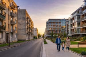 Late afternoon in Sarcelles showing contrasting old and modern residential buildings with a family walking on a clean sidewalk.