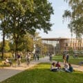 Étudiants se promenant, faisant du vélo et travaillant sur la pelouse devant des bâtiments modernes et arborés.