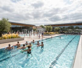 Bassin extérieur de la piscine de Hautepierre avec des personnes faisant de l'aquagym et des enfants jouant dans l'eau.