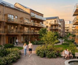 Résidence moderne avec jardins paysagers, balcons en bois et familles profitant d'un espace extérieur ensoleillé.