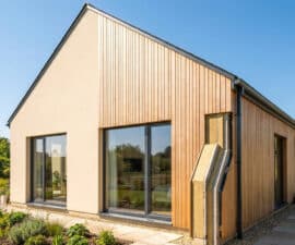 Pignon de maison moderne avec bardage bois et coupe montrant l'isolation thermique extérieure.