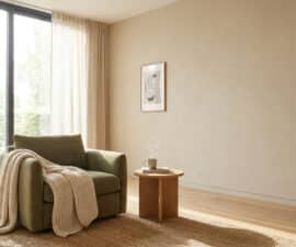Un fauteuil vert confortable avec un plaid près d'une fenêtre et une tasse fumante, évoquant un intérieur douillet.