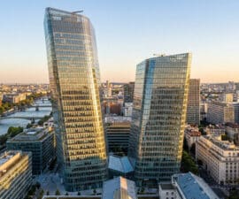 Vue aérienne panoramique des Tours Duo en verre asymétriques dominant les bords de Seine à Paris au coucher du soleil.